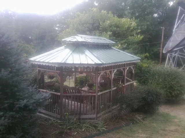 Green metal roof on a backyard gazebo surrounded by garden beds in Hudson