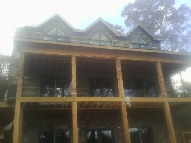 Dormers and porch framing on a large log home under construction — Roof Coating work by our crew in Hudson
